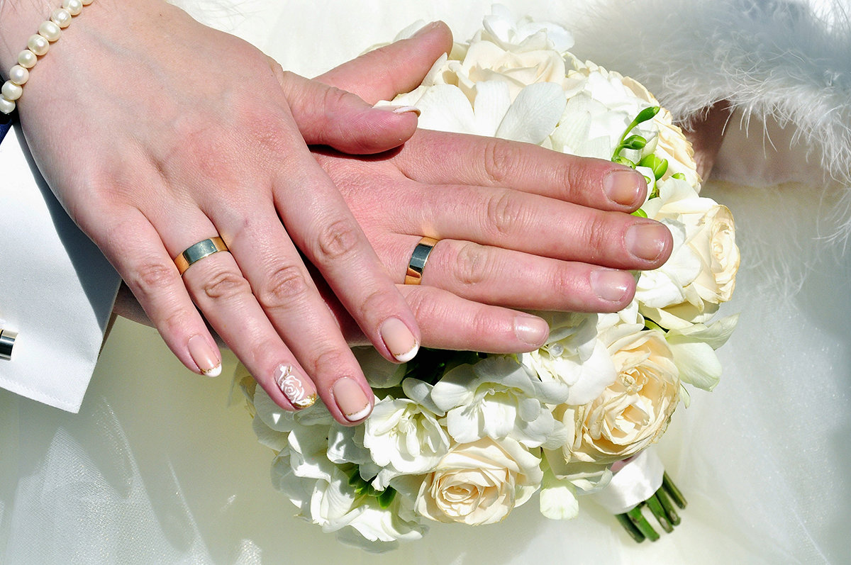 Обручальные кольца на пальцах жениха и невесты